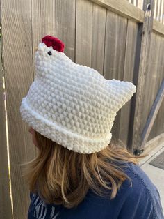 a woman wearing a knitted hello kitty hat with a red flower on the top