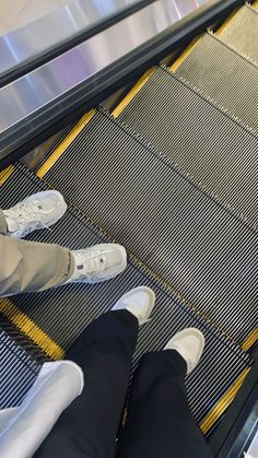 two people standing on an escalator with their feet up