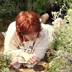 a woman sitting on the ground next to some plants