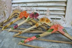 four wooden clothes pegs with flowers painted on them sitting in front of an old window