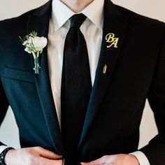 a man wearing a black suit with a boutonniere on his lapel