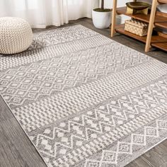 a large rug with an intricate design on the floor in front of a white window