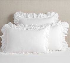 three white pillows with ruffled edges on a bed