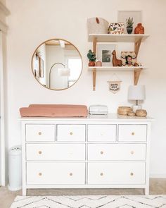 a white dresser topped with lots of drawers and a mirror over it's top