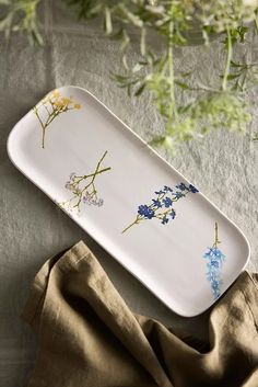 a white tray with blue and yellow flowers on it next to some brown napkins