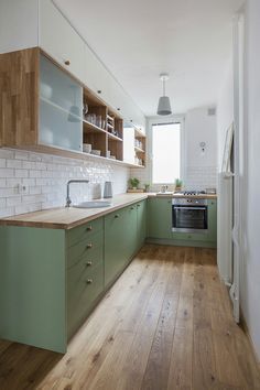 a kitchen with green cabinets and wooden floors is pictured in this image from the front view