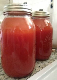 two jars filled with liquid sitting on top of a counter