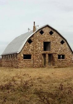 an old stone barn sits in the middle of a field