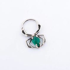 a silver ring with a green stone in the center on a white background, it looks like an insect