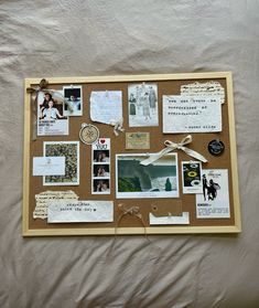 a cork board with pictures, photos and other things attached to it on a bed