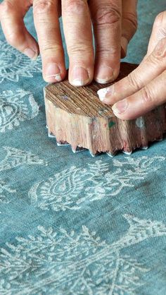 an older woman is using a small wooden block to work on something with her hands