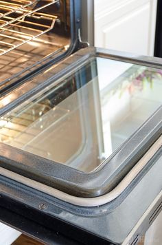 an oven door is open to show the inside of it's glass trays