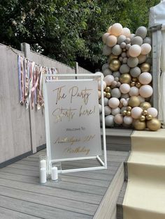 a party sign sitting on top of a wooden floor next to balloons and streamers