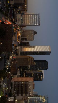 the city skyline is lit up at night with skyscrapers in the foreground and street lights on either side