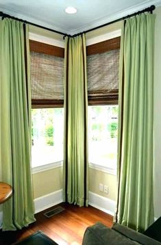 a living room filled with furniture and two windows covered in green drapes next to a wooden floor