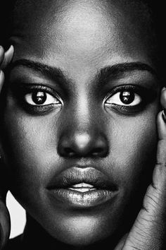 a black and white photo of a woman's face with her hands on her head