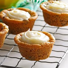 small cupcakes with white frosting sitting on a cooling rack