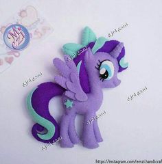 a purple pony with blue eyes laying on top of a white table next to a sticker