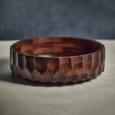 a wooden bowl sitting on top of a table next to a gray wall and floor