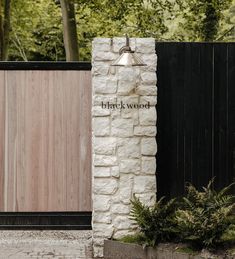 a stone wall with a wooden gate in front of it that says brickwood on the side