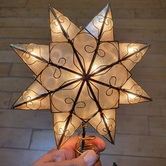 a person holding up a lighted star ornament