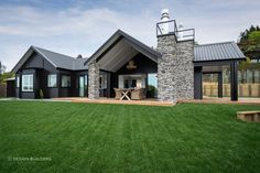 a black house with a stone chimney and covered patio