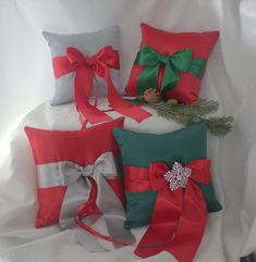 four christmas pillows with bows and pine cones on them, all wrapped in red and green