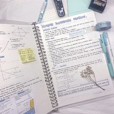 an open notebook with notes and pens on it next to a cell phone, pen and calculator