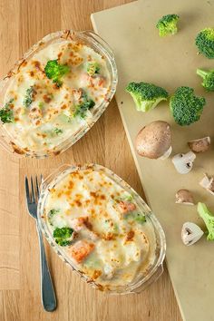 two casserole dishes with broccoli, mushrooms and cheese on a cutting board