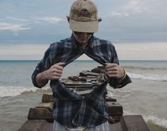 a man standing on top of a wooden pier next to the ocean