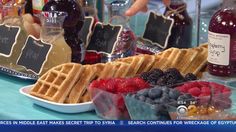 some waffles and berries are on a table with wine bottles in the background