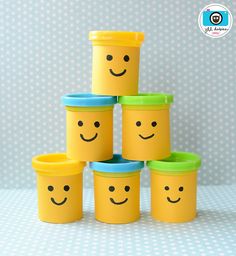 six yellow plastic cups with faces painted on them