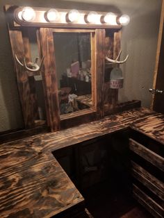 a wooden vanity with lights on it and a mirror in the corner next to it