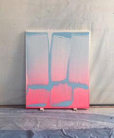 an abstract painting with pink and blue colors on a gray background, in the process of being painted