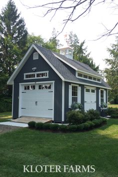 a small gray and white house with two garages on the front, surrounded by green grass