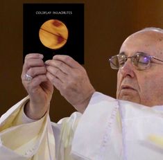 an older man holding up a book in front of his face with the image of saturn on it