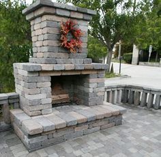 a brick fireplace with a wreath on it in the middle of a stone patio area