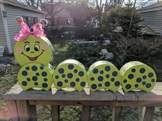 a green and black polka dot caterpillar sitting on top of a wooden fence