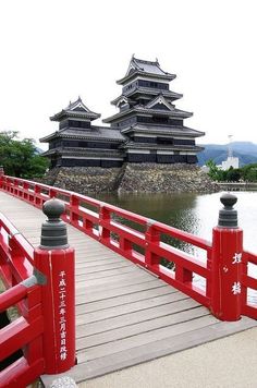 a bridge that has some red railings on it and two buildings in the background