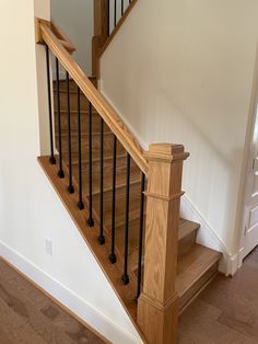 a wooden stair case next to a white wall