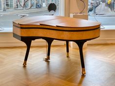 a grand piano sitting on top of a hard wood floor in front of a window