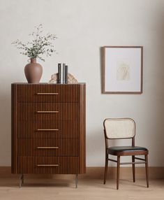 a wooden cabinet with drawers and a chair next to it in front of a white wall