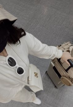 a woman in white jacket and sunglasses pulling luggage