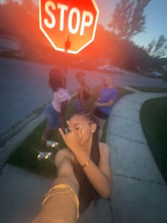 a group of people standing on the side of a road next to a stop sign