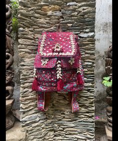 a colorful backpack hanging on a stone wall