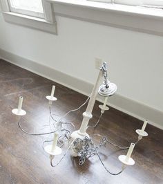 a chandelier that is sitting on the floor in front of a window with wires attached to it