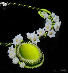 a green necklace with white flowers on it