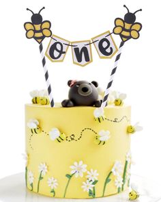 a yellow cake topped with a teddy bear and two bees