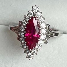 a ring with a large red stone surrounded by small white diamonds on top of it