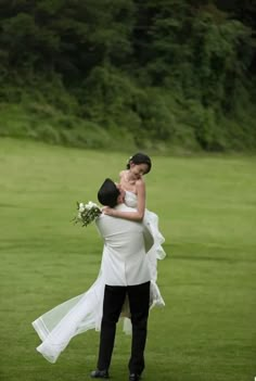 a bride and groom hugging in the grass